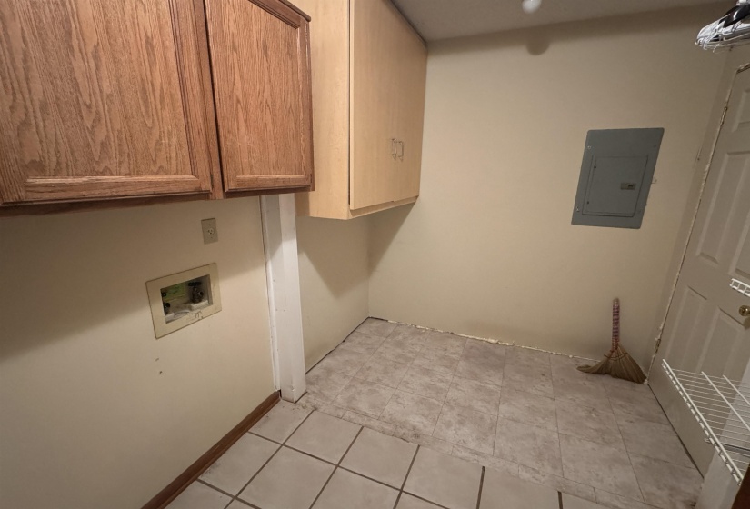 Washroom with electric panel, cabinet space, and washer hookup