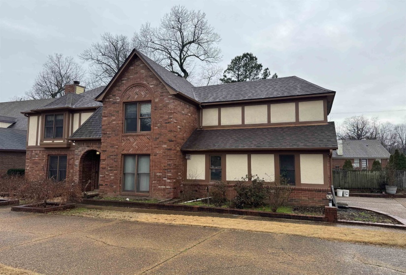 English style home with brick siding, roof with shingles, a chimney, and stucco siding