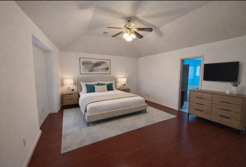 Bedroom featuring dark wood finished floors, a textured ceiling, vaulted ceiling, ceiling fan, and ensuite bath