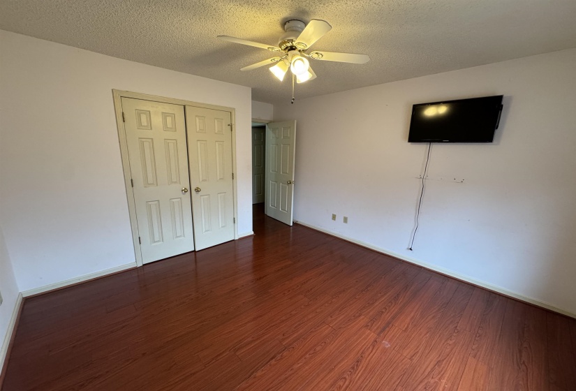 Unfurnished bedroom with dark wood-style flooring, a closet, a ceiling fan, and a textured ceiling