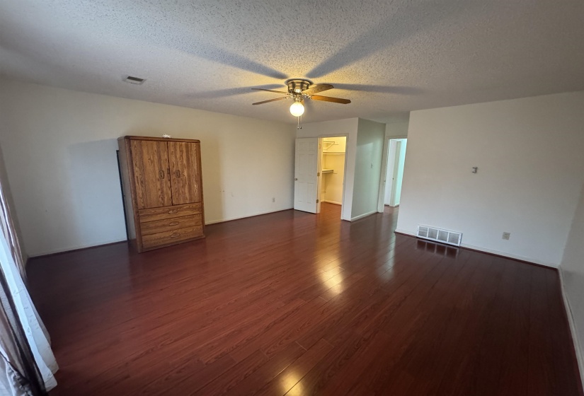Empty room featuring dark wood-style flooring, a textured ceiling, and ceiling fan
