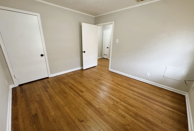 Unfurnished bedroom with hardwood / wood-style flooring and ornamental molding
