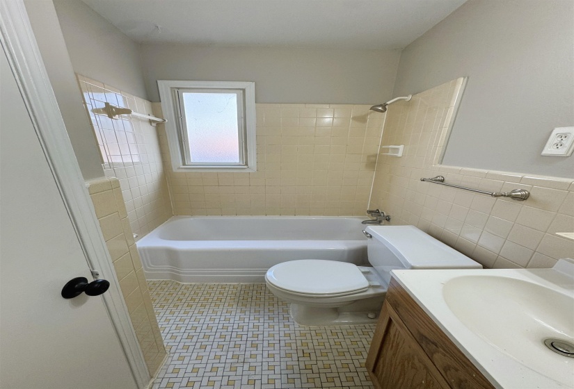 Bathroom featuring  shower combination, tile walls, vanity, and wainscoting