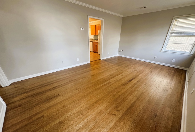 Spare room with ornamental molding and light wood-type flooring