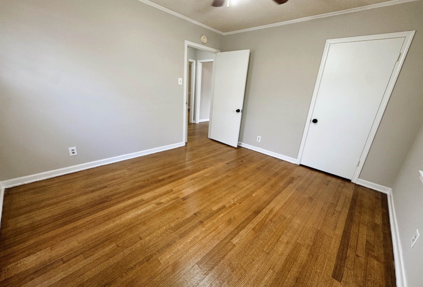 Unfurnished bedroom featuring light wood-type flooring, crown molding, and a ceiling fan