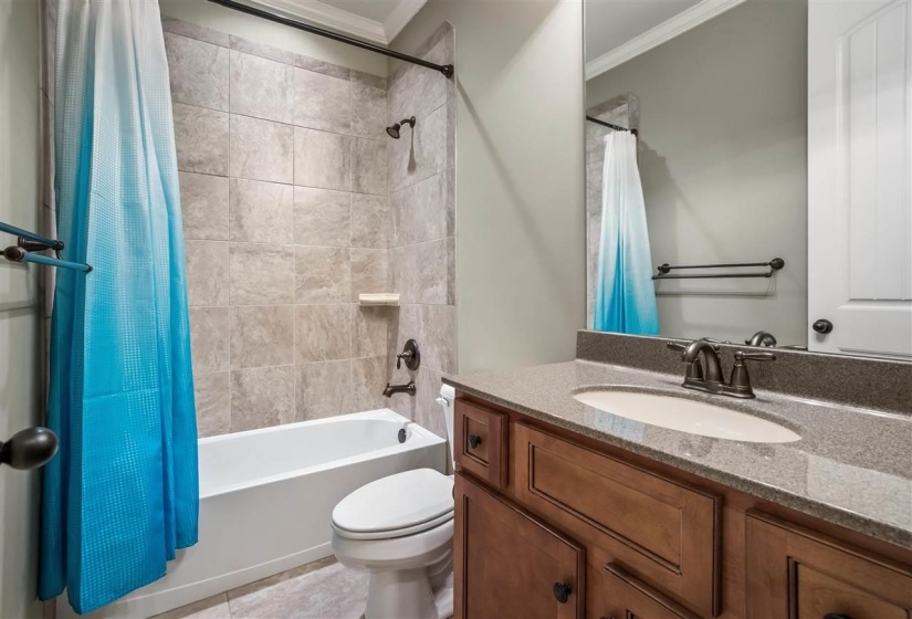 Bathroom with vanity, shower / tub combo with curtain, and ornamental molding