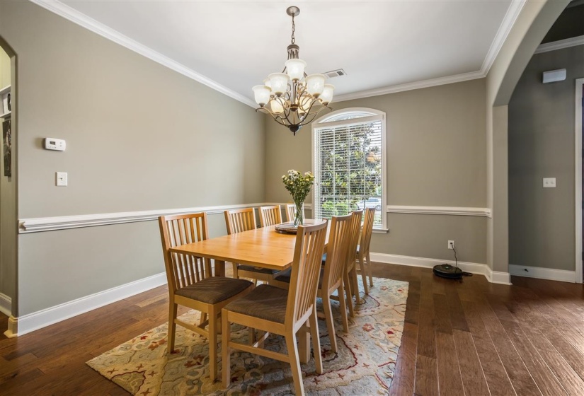 Dining space featuring arched walkways, ornamental molding, dark wood-style flooring, and a chandelier