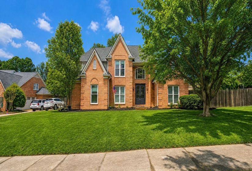 Traditional-style house with brick siding, a shingled roof, and a front lawn