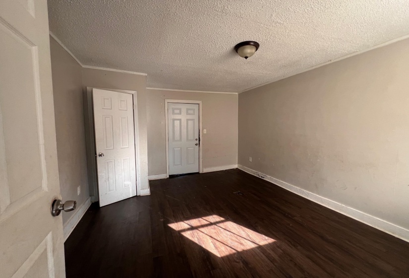 Unfurnished bedroom featuring dark wood-type flooring, a textured ceiling, and crown molding