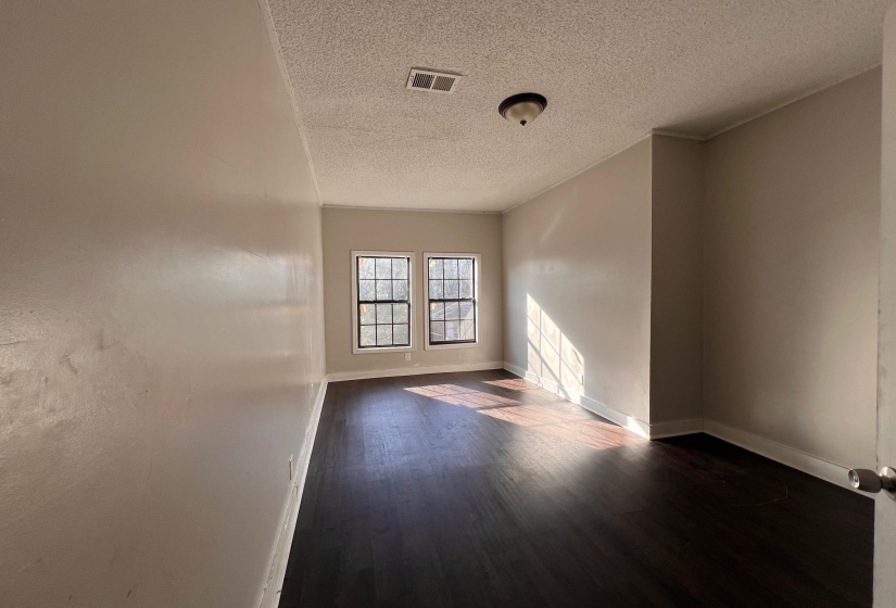Empty room featuring dark wood-style flooring and a textured ceiling