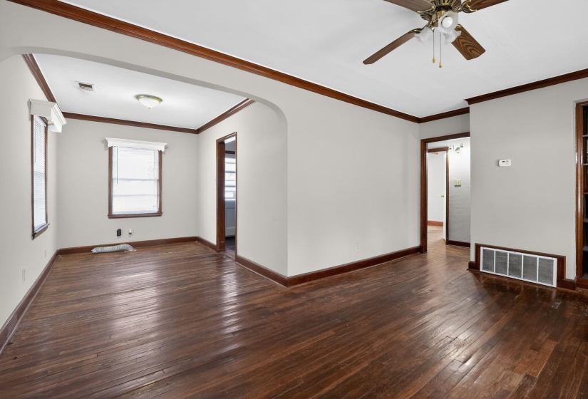 Spare room with arched walkways, dark wood finished floors, crown molding, and ceiling fan
