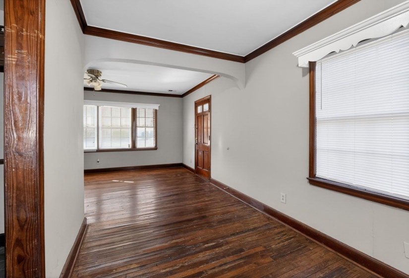 Spare room featuring dark wood-type flooring, ornamental molding, arched walkways, and a ceiling fan