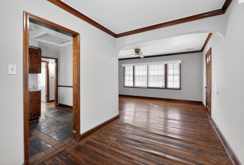 Unfurnished room with dark wood finished floors, arched walkways, ceiling fan, and crown molding