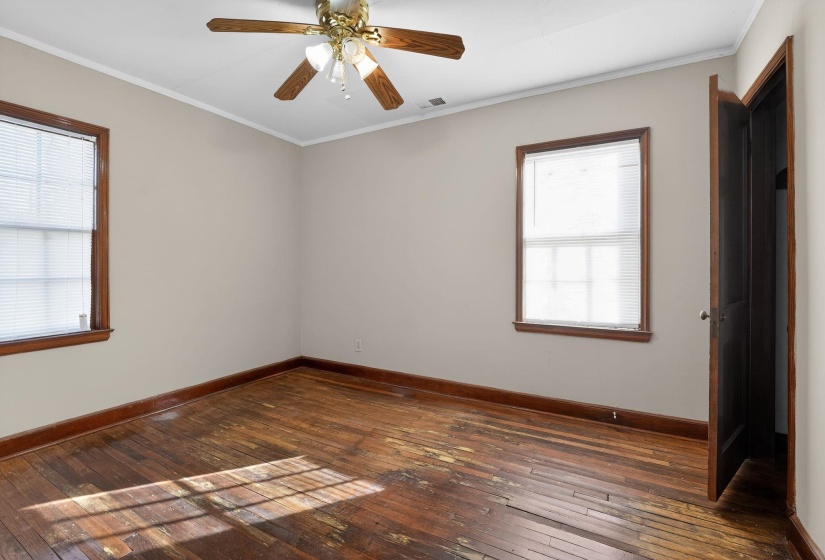 Empty room featuring dark wood-style floors, crown molding, and ceiling fan