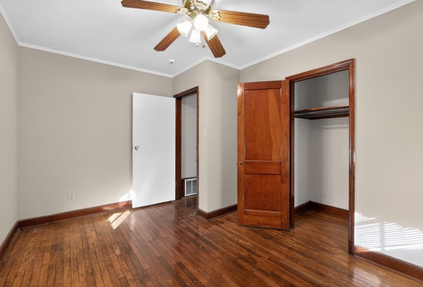 Unfurnished bedroom with ornamental molding, dark wood-style floors, a closet, and ceiling fan