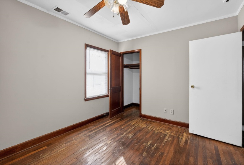 Unfurnished bedroom with dark wood-style flooring, ornamental molding, a closet, and ceiling fan