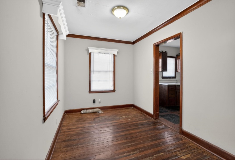 Unfurnished bedroom featuring dark wood-style flooring, multiple windows, crown molding, and ensuite bathroom
