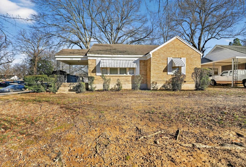 Bungalow-style home featuring brick siding, covered porch, and a carport