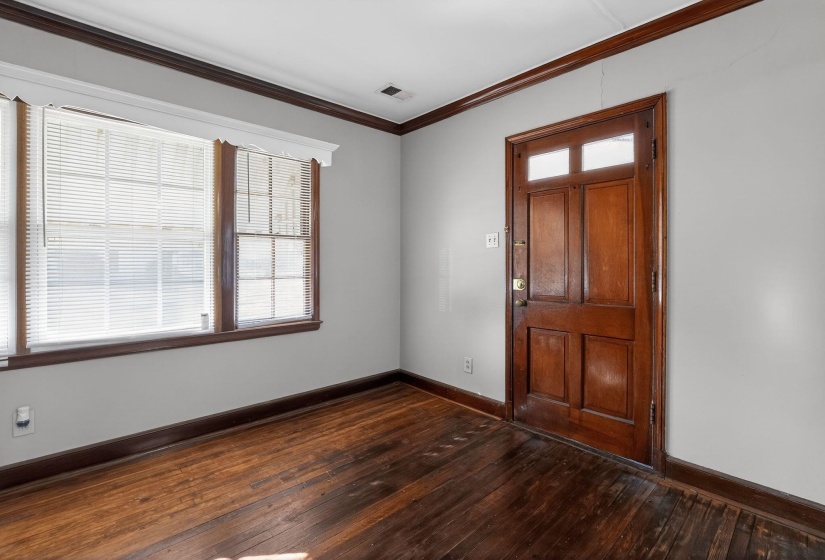Foyer entrance with ornamental molding and dark wood-type flooring