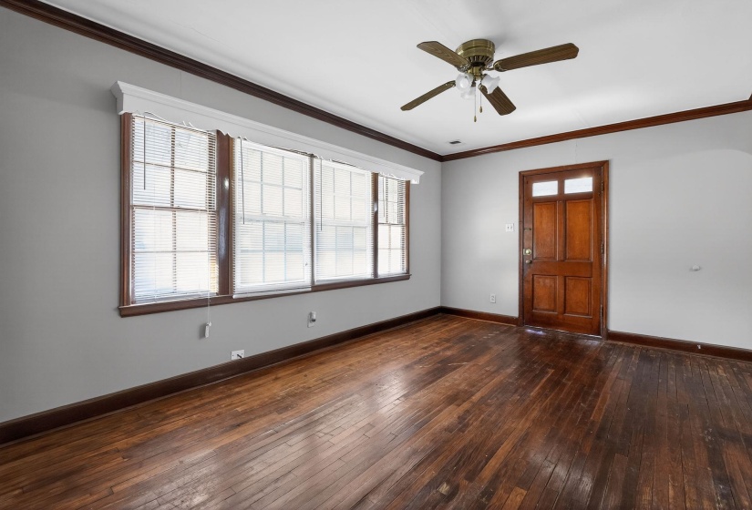 Foyer entrance with ornamental molding, a ceiling fan, and dark wood-style floors