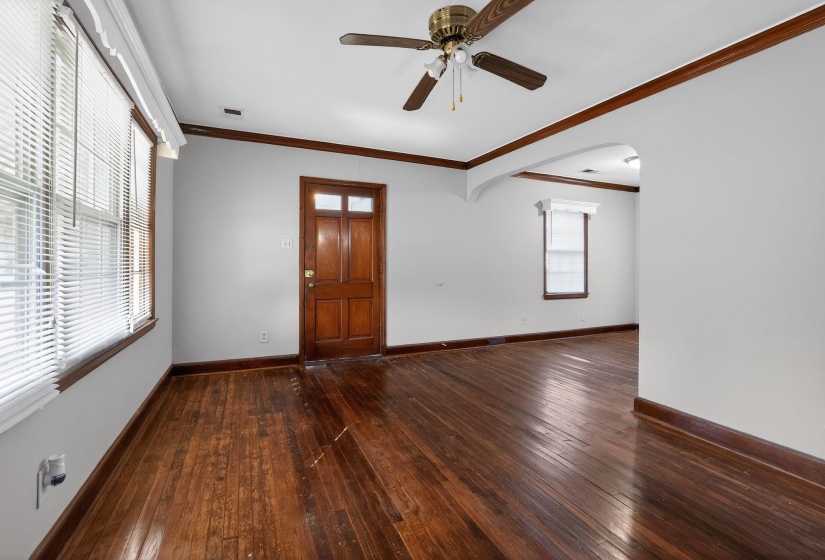 Foyer with arched walkways, crown molding, dark wood-type flooring, and a ceiling fan