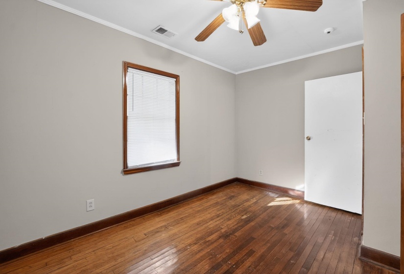 Empty room featuring ornamental molding, dark wood-type flooring, and ceiling fan