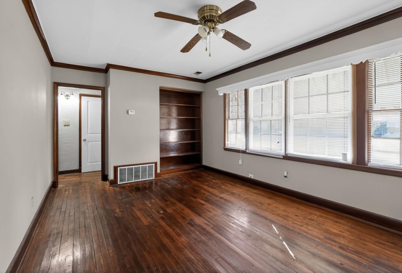 Unfurnished living room with dark wood finished floors, crown molding, and a ceiling fan