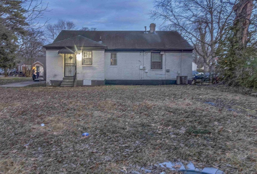 Back of house featuring brick siding and a chimney