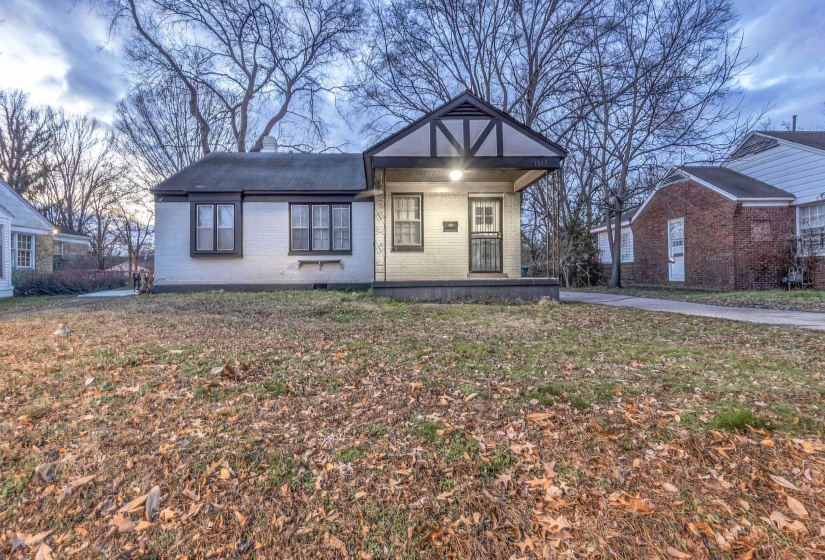 View of front of house with brick siding, a front lawn, and covered porch