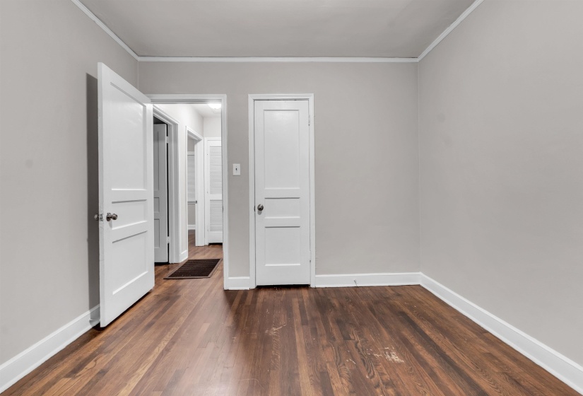 Unfurnished bedroom with dark wood finished floors, ornamental molding, and a closet