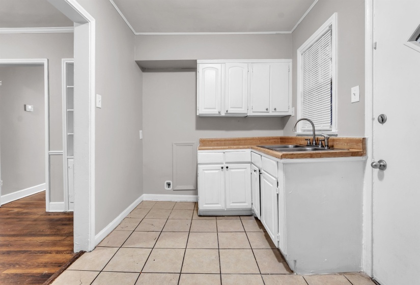 Laundry room featuring crown molding and light tile patterned floors
