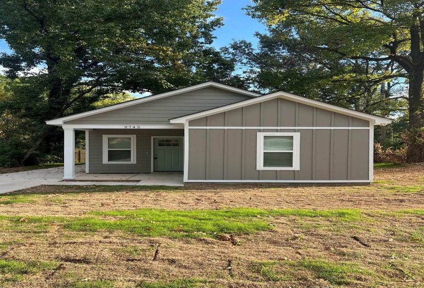 View of front of property featuring board and batten siding, a patio, and a front yard