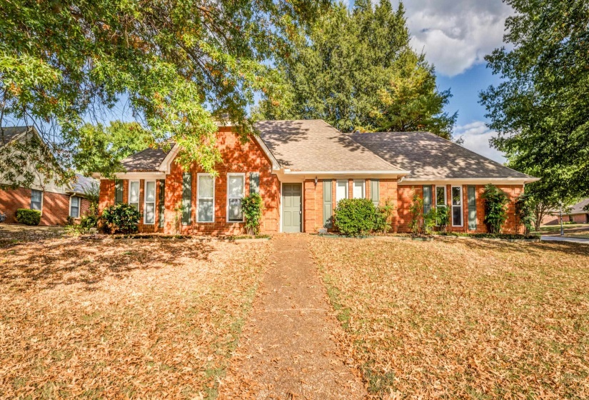 Ranch-style house featuring a shingled roof, brick siding, and a front yard