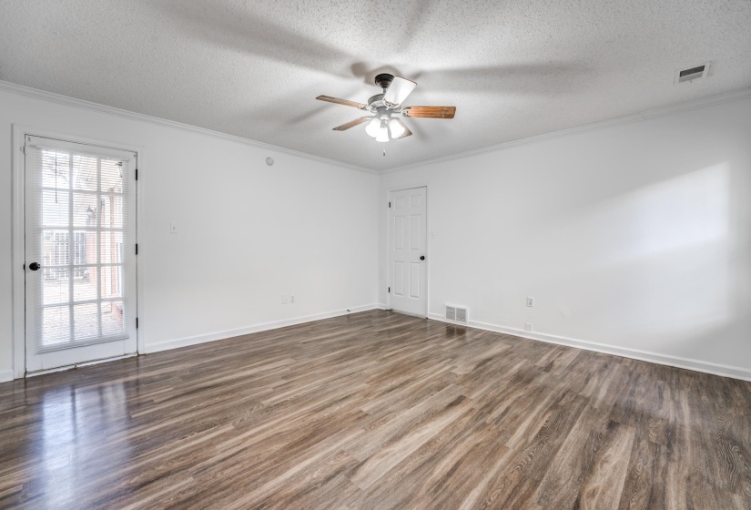Empty room featuring a textured ceiling, dark wood-style flooring, crown molding, and a ceiling fan