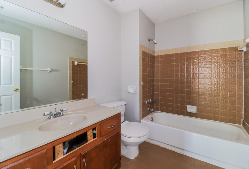 Bathroom with washtub / shower combination, vanity, and dark tile patterned floors