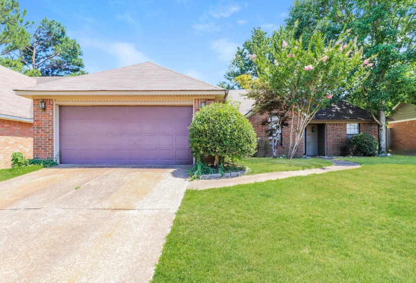 Ranch-style home with brick siding, driveway, a front lawn, and an attached garage