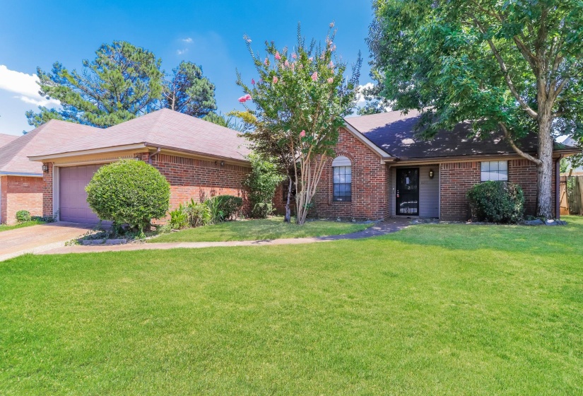Ranch-style home featuring a front yard, brick siding, and a garage