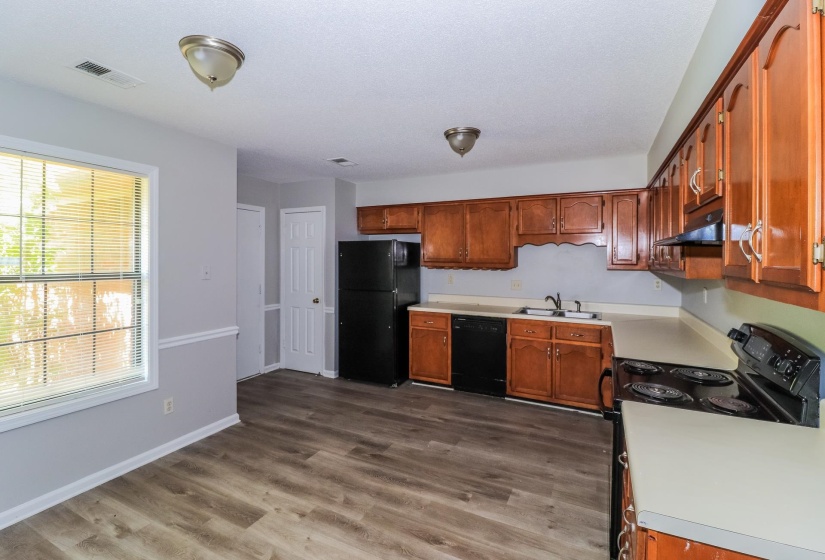 Kitchen with black appliances, light countertops, light wood-style flooring, and brown cabinetry
