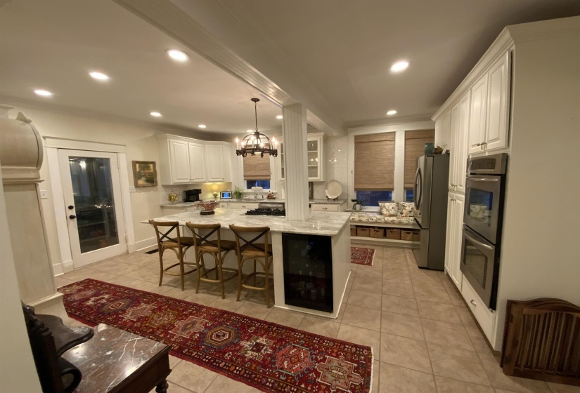 Kitchen with white cabinetry, light stone counters, wine cooler, a breakfast bar, and recessed lighting