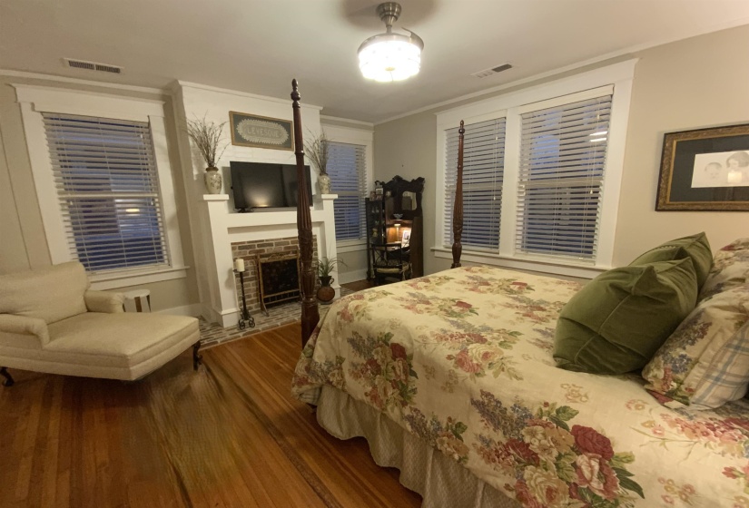 Bedroom featuring dark wood-style floors, crown molding, and a brick fireplace