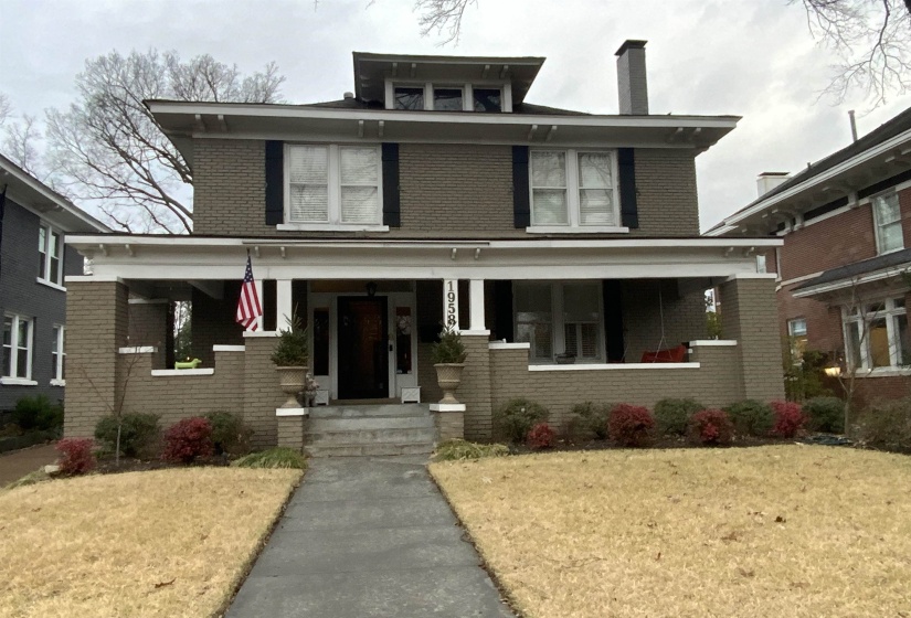 Traditional style home featuring brick siding, covered porch, a chimney, and a front lawn