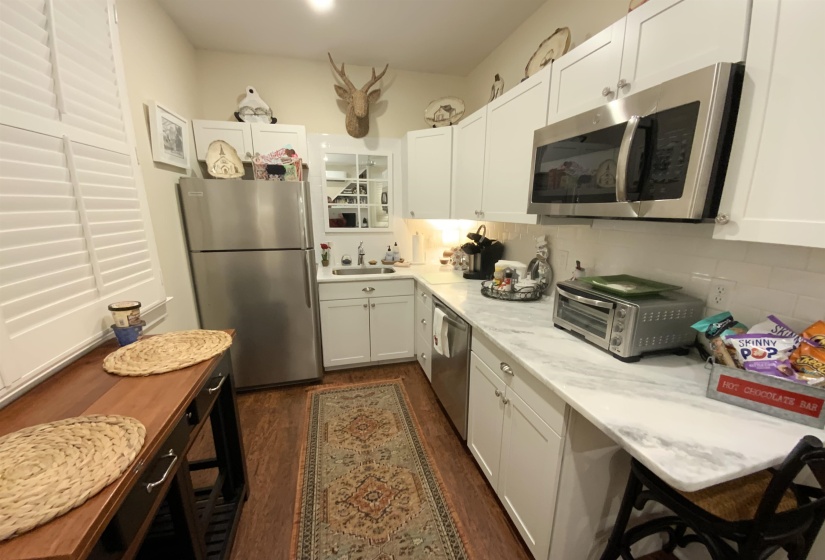 Kitchen featuring appliances with stainless steel finishes, white cabinets, dark wood finished floors, and decorative backsplash