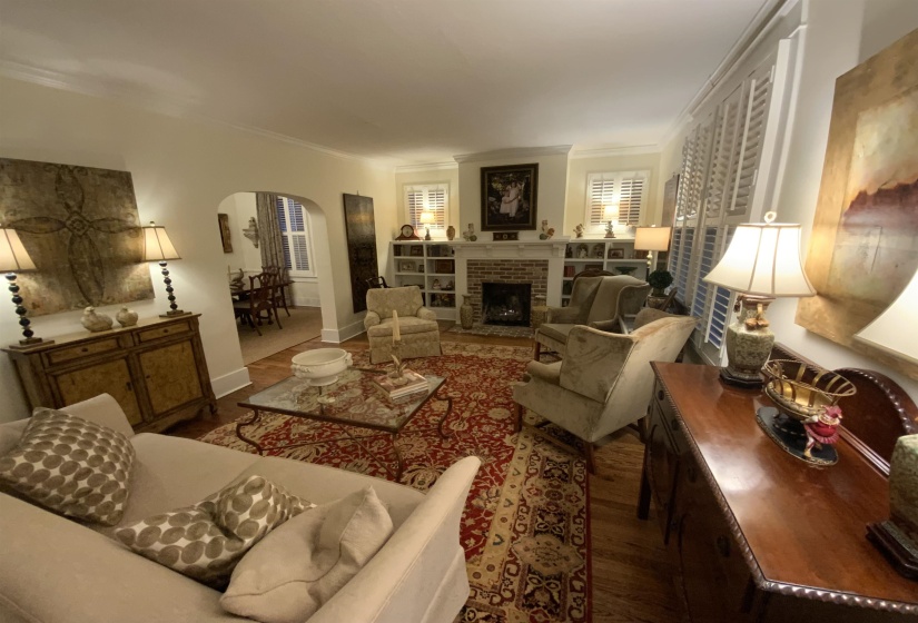 Living area with arched walkways, ornamental molding, a fireplace, and wood finished floors