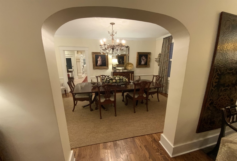 Dining space with arched walkways, wood finished floors, and a chandelier