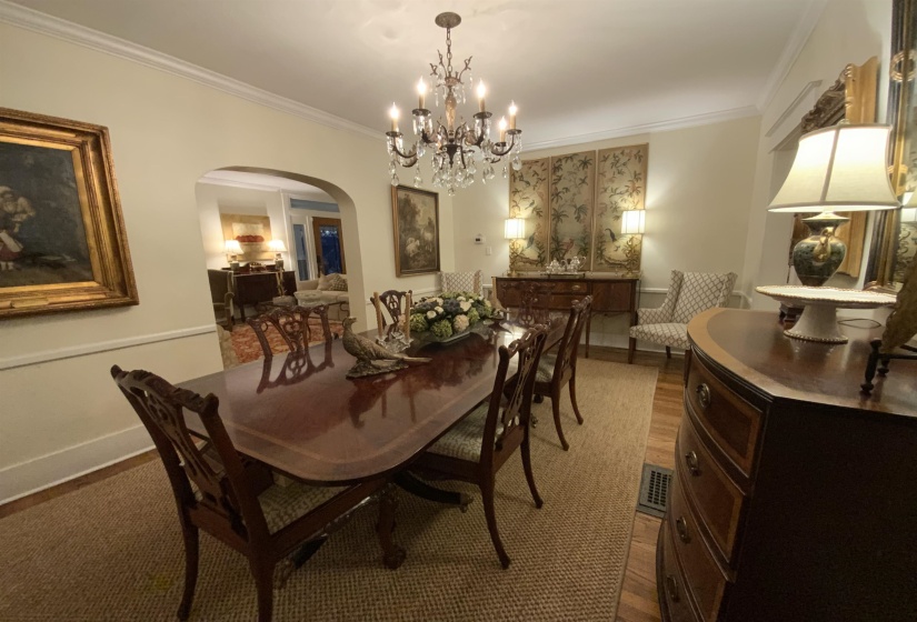 Dining space with arched walkways, ornamental molding, wood finished floors, and a chandelier