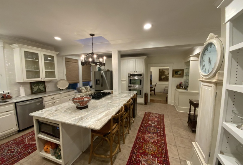 Kitchen featuring open shelves, glass insert cabinets, white cabinets, stainless steel appliances, and decorative light fixtures