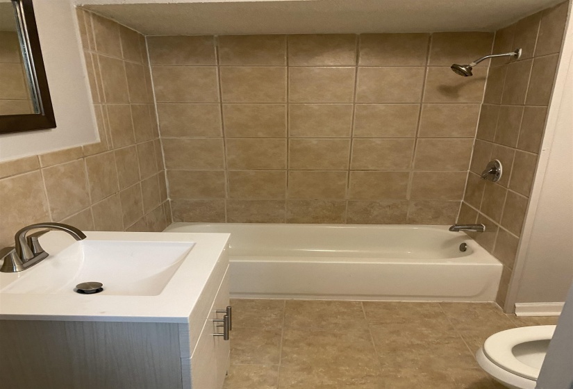 Bathroom featuring vanity, shower / tub combination, and light tile patterned floors