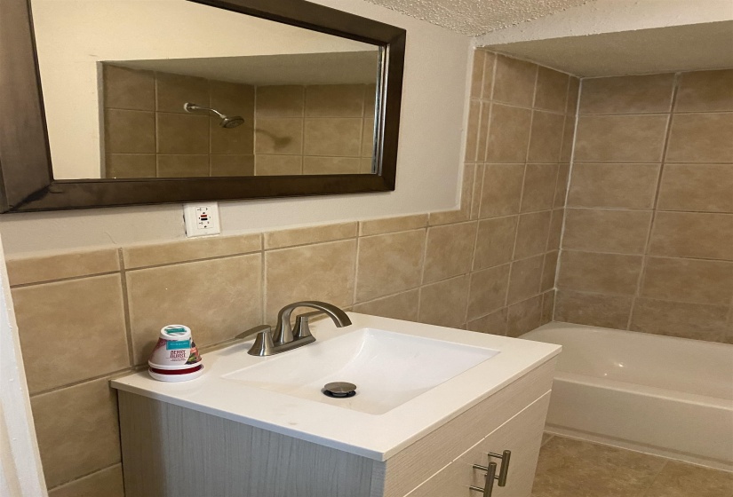 Full bath with vanity, tile walls, a textured ceiling, shower / washtub combination, and tasteful backsplash