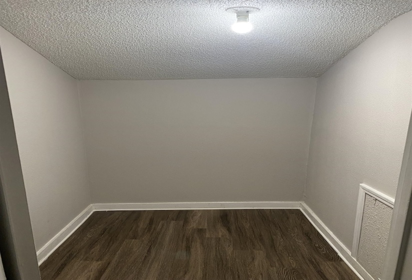 Empty room with dark wood finished floors and a textured ceiling