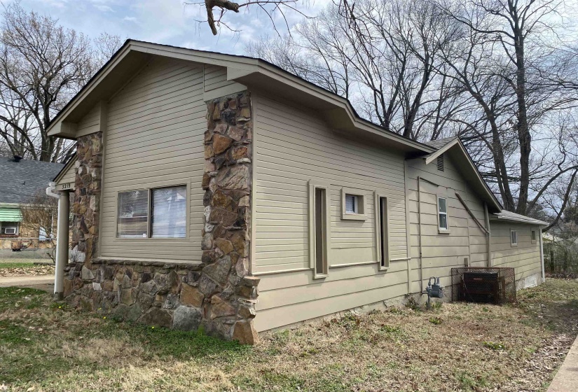 View of property exterior with stone siding and a cooling unit